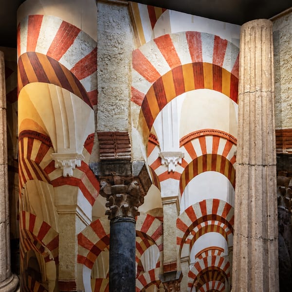 Ornate interior featuring layered red-and-white horseshoe arches, carved columns, and a dark blue decorative pillar.