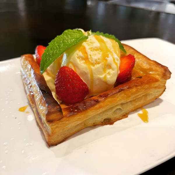 Puff pastry dessert with vanilla ice cream, strawberries, mint, and a caramel drizzle.