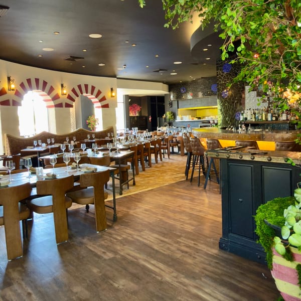A restaurant interior with set tables, a bar area, and decorative arches with red and white stripes.